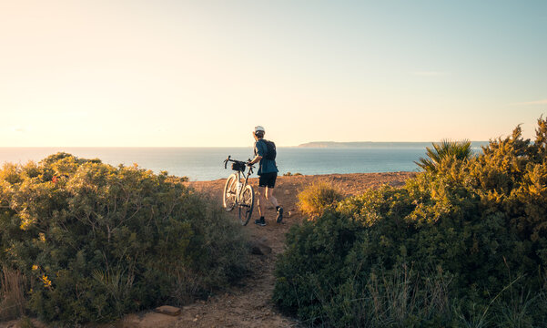 Cyclist with bike enjoying seaside view at sunset, Zahara de los Atunes