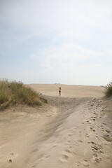 Woman walking in between the sand dunes