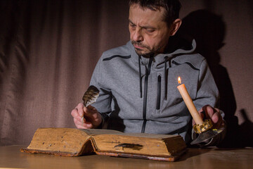 A man reads an old book by candlelight.