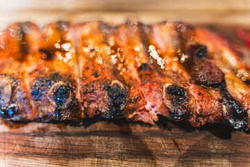 Top view of delicious grilled pork ribs with ketchup and mustard served on a wooden board. A dish for beer in a meat restaurant. Selected Focus