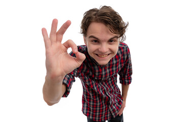 A young man in a plaid shirt smiling and making an okay gesture against a white background.