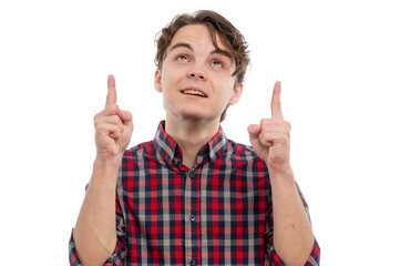 A young man in a checkered shirt looking up and pointing with both hands against a white background.