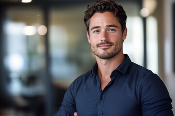 Naklejka premium Confident young man smiling in a professional business environment with blurred background