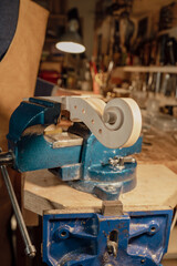 Luthier working on violin scroll using a bench vise in his workshop