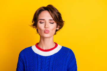 Photo portrait of pretty young girl closed eyes kissing girlfriend dressed stylish blue knitted outfit isolated on yellow color background