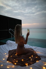 Woman sipping champagne with the sunset over the ocean