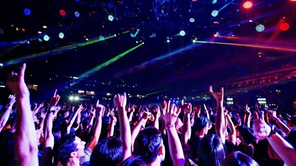 Vibrant concert scene with a crowd raising hands, captured from a low-angle. Dynamic lighting creates an energetic video atmosphere.