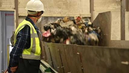 Worker monitors waste sorting process in recycling facility on a busy day
