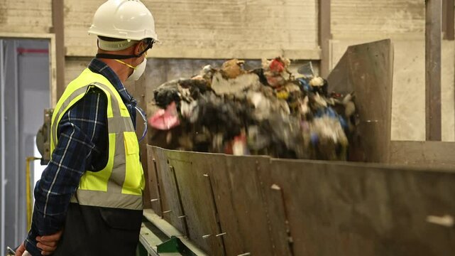 Worker monitors waste sorting process in recycling facility on a busy day
