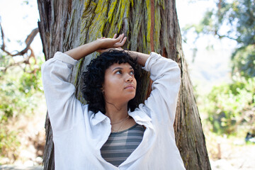 Young woman leaning against a tree in a park