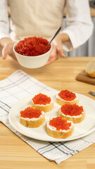Woman's hand holding a toast with red salmon caviar