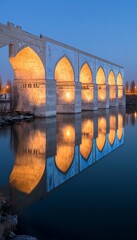 Illuminated Siosepol Bridge with Reflections in a Serene River at Twilight, Esfahan, Iran
