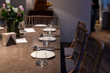 Elegant dining table set in a cozy restaurant with modern rustic decor. A beautifully arranged dinner setting featuring ceramic plates, glassware, and neatly placed cutlery. The warm ambient lighting 