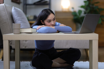 A woman sitting at home is sad, disappointed and upset, She was absent-mindedly looking at the laptop. People are disappointed in love.
