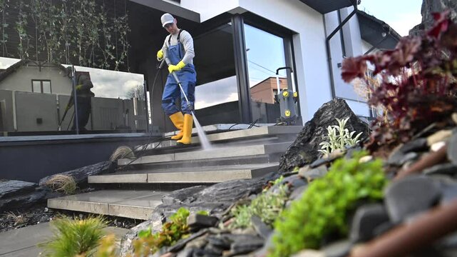 Cleaning outdoor steps with pressure washer and landscaping details in residential area