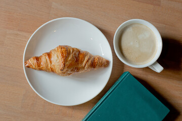  Coffee and croissant on the wooden table with book