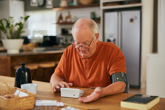 Happy old man measuring blood pressure at home