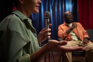 Speaking into microphone with gesturing at live event while an audience member is watching...
