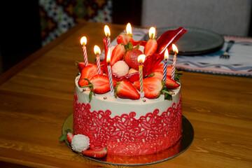 Birthday cake with strawberries and candles on the table. Selective focus.