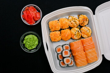 Sushi set in a white box on a black background, top view. Food delivery © Sasha