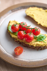 Macro shot of rye bread tost topped with hummus and colorful vegetables for a helthy snack. Breakfast, brunch concept, healthy lifestyle 