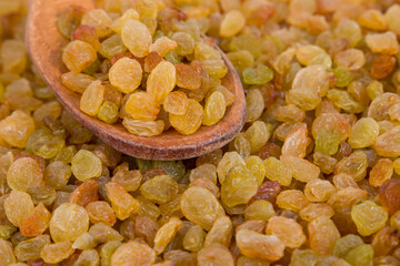 Raisins in a wooden spoon on a background of dried grapes