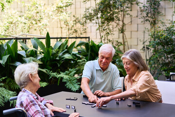 Seniors enjoying a board game outdoors in a rehabilitation facility garden