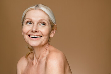 Headshot of gorgeous beautiful middle-aged woman with pure and healthy skin and blonde hair, stands...