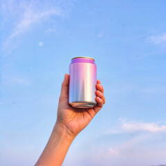 A stylish and modern beverage can held against a bright blue sky.
