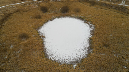 Small pond is surrounded by tall grass. Frozen channels of the great Russian Volga River.