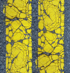 close up cracked yellow line on asphalt surface