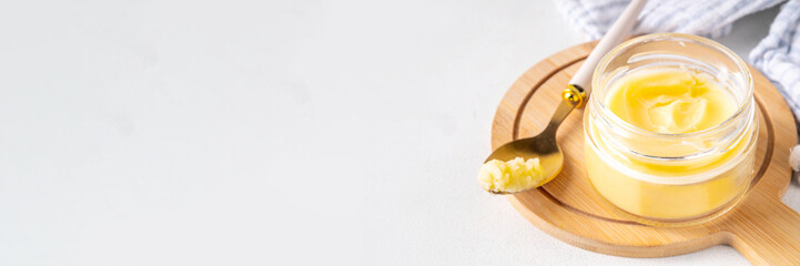 Homemade ghee butter in small glass jar on white kitchen table background, copy space. Melted organic ghee clarified butter, Bio Ayurveda Lactose free high quality animal fat source
