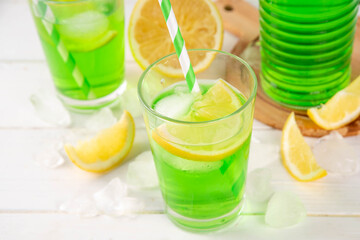 Tarragon summer cold lemonade, green aromatic refreshing cocktail with tarragon syrup or liqueur and lemon, on a white wooden kitchen table