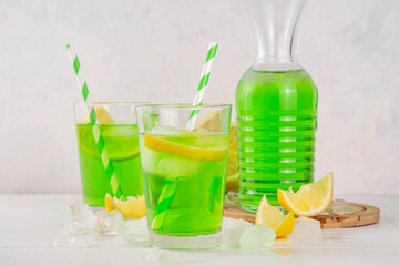 Tarragon summer cold lemonade, green aromatic refreshing cocktail with tarragon syrup or liqueur and lemon, on a white wooden kitchen table