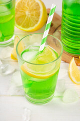 Tarragon summer cold lemonade, green aromatic refreshing cocktail with tarragon syrup or liqueur and lemon, on a white wooden kitchen table