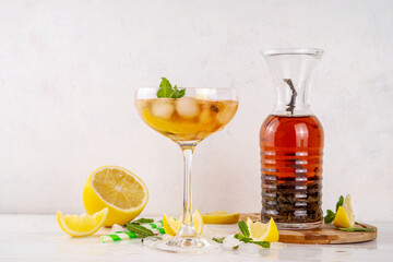 Infused tasty iced tea cocktails martini cocktail with lemon and mint, tasty refreshing non-alcohol mocktail on white wooden table background 