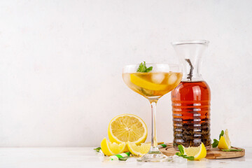 Infused tasty iced tea cocktails martini cocktail with lemon and mint, tasty refreshing non-alcohol mocktail on white wooden table background 