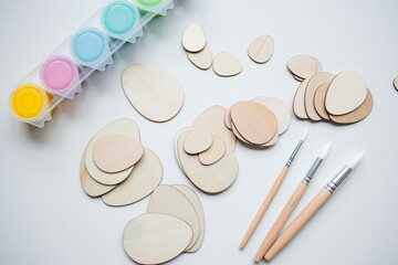 Wooden Easter egg shapes and paints with brushes for DIY crafting projects