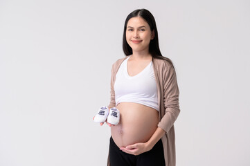 Portrait of Beautiful pregnant woman holding baby shoes over white background studio