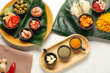 Cut banana leaves with different food, spices and sauce on white table, flat lay. Healthy eco serving