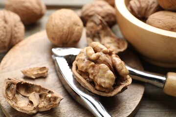 Fresh walnuts and nutcracker on table, closeup