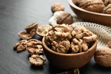 Fresh ripe walnuts and shells on black table, closeup. Space for text