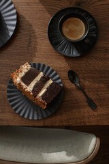 Dark chocolate handmade cake served on black plate on oak table