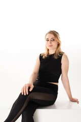 Young woman poses confidently in athletic wear against a minimalist white background in a studio...