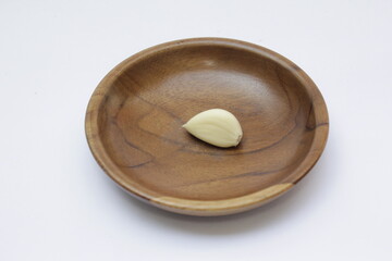 Closeup of a Garlic or Allium sativum on wooden plate with a white background
