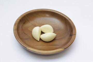 Closeup of Garlic or Allium sativum on wooden plate with a white background