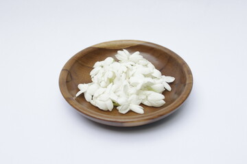 A bunch of White Jasmine or Jasminum sambac flowers in a small wooden bowl on a white background
