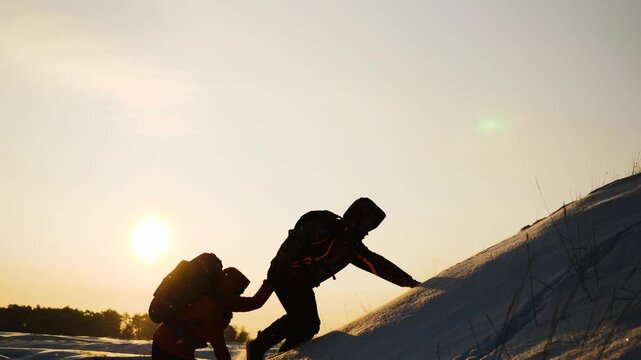 teamwork business. overcome difficulties by giving helping hand fellow partner. two people with backpacks sunset. climber pulls his comrade hand up snowy mountain. go victory. teamwork win. silhouette