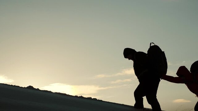 travelers climb snowy mountain sunset winter. hiking concept winter. teamwork. group people travel through snow. climbers with backpacks. going uphill top. mutual victory success. achieving path