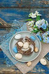 Easter table setting with eggs, bird's nest and blooming branch. Traditional festive symbols